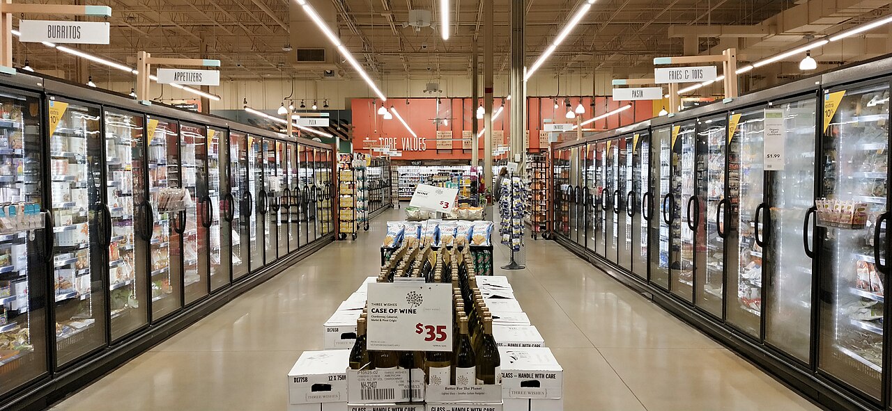 Une allée bordée de congélateurs à portes vitrées dans un commerce