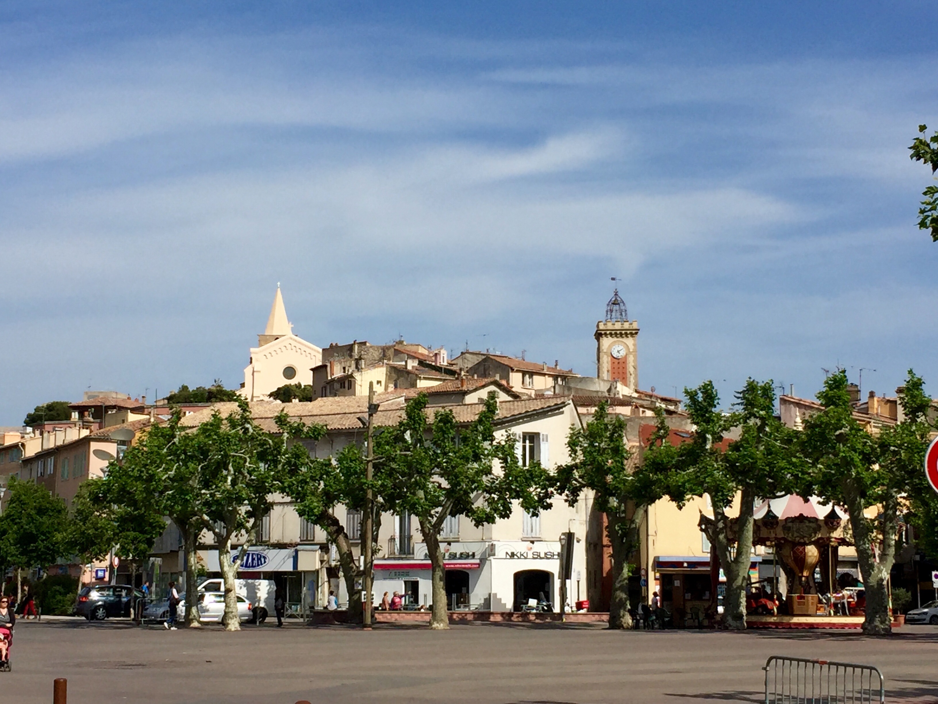 Les façades de la vieille ville d’Aubagne, derrière une rangée d’arbres