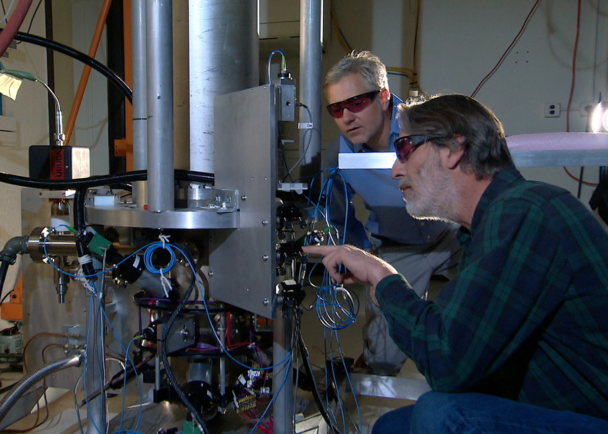 Deux chercheurs portant des lunettes de protection travaillent près de l’horloge atomique NIST-F2