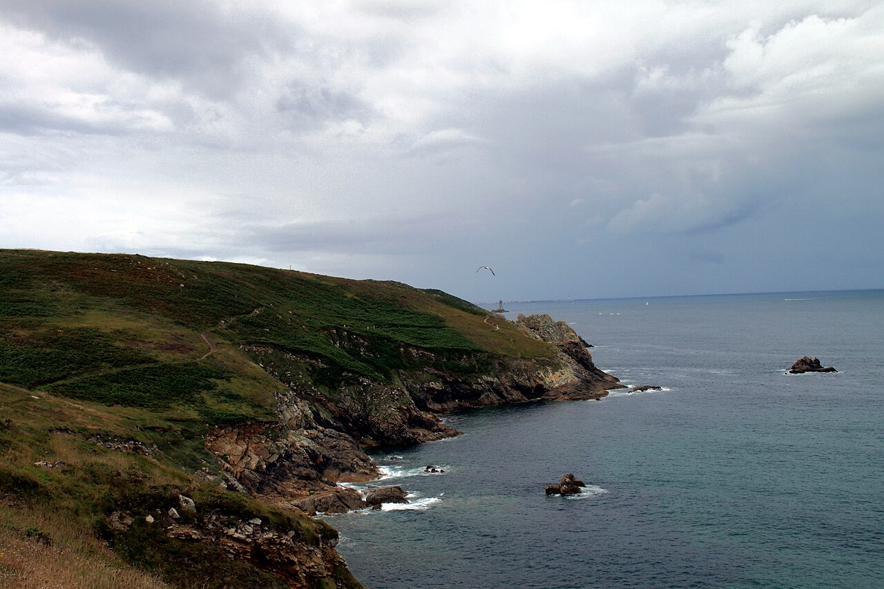 La côte rocheuse de la pointe du Raz, avec la mer et un phare à l’horizon