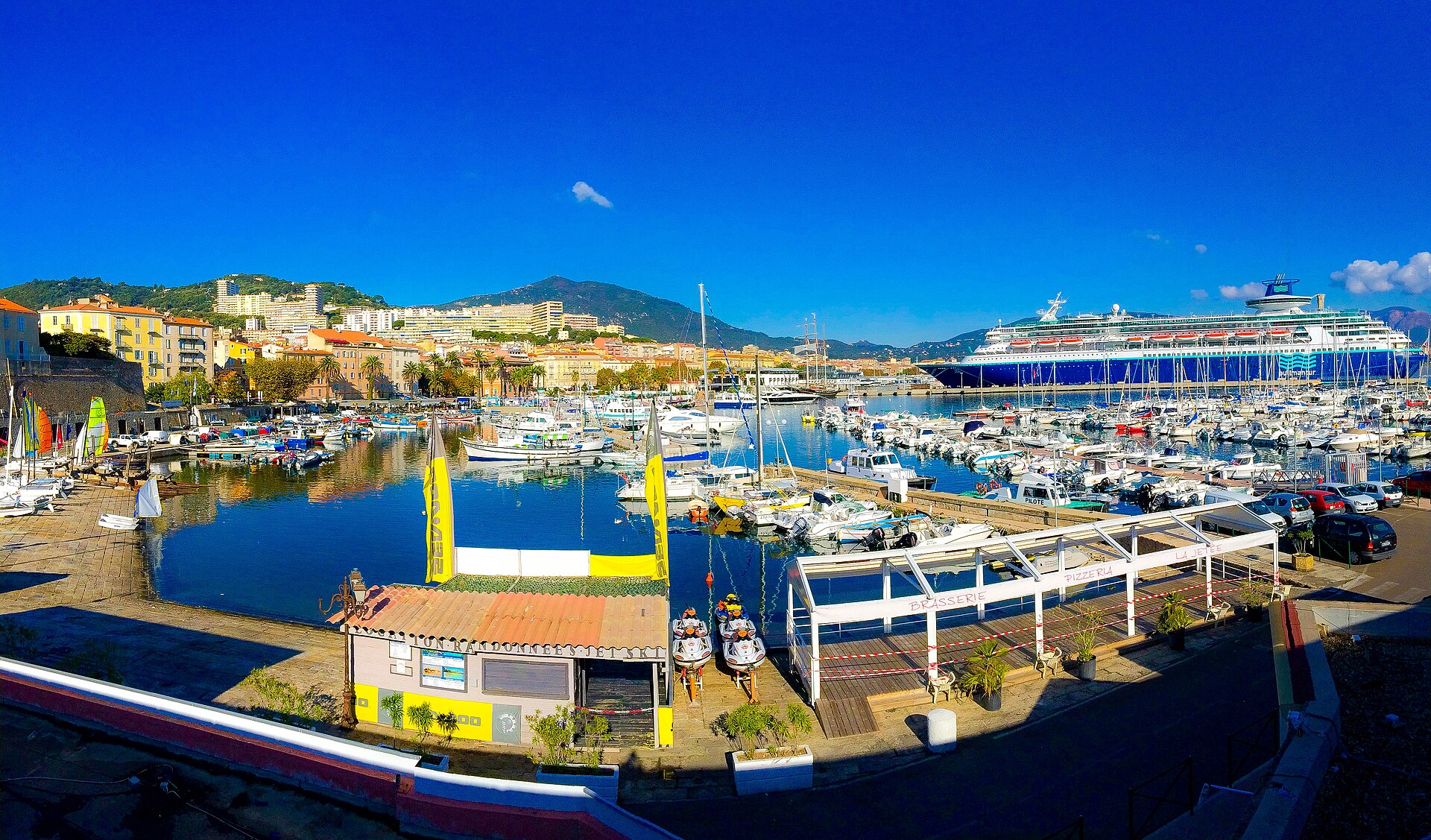 Le port Tino-Rossi à Ajaccio, avec des voiliers et la ville en arrière-plan.
