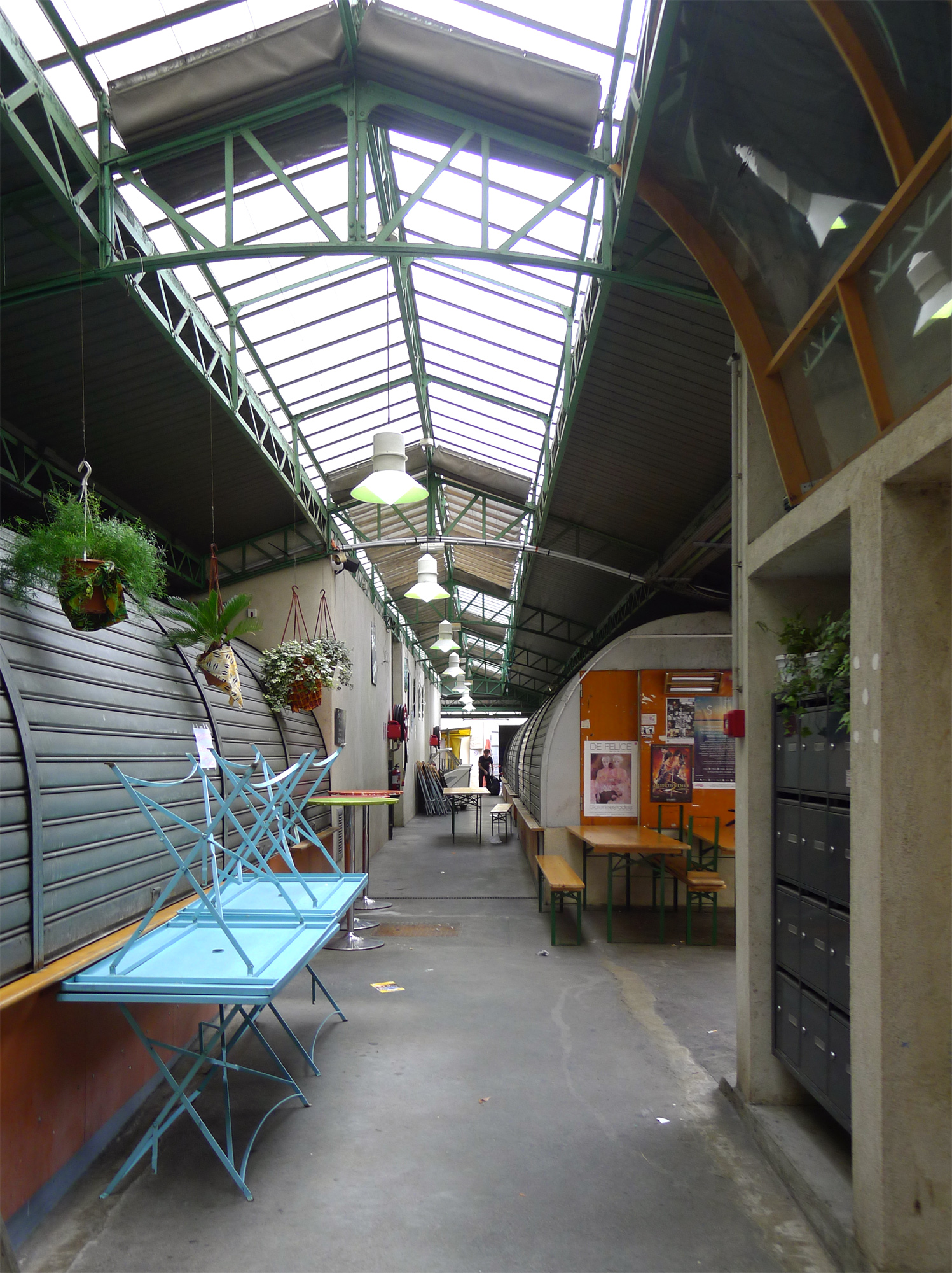 Une allée couverte du marché des Enfants-Rouges à Paris, avec des étals fermés et des tables.