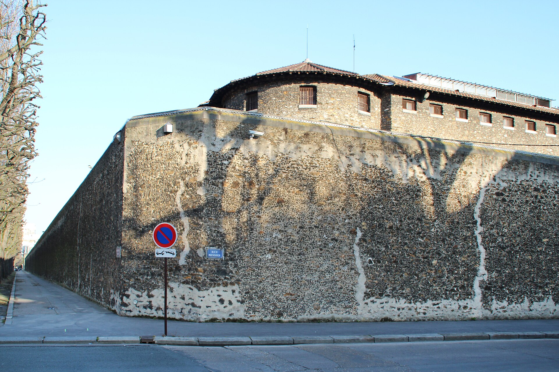 Le mur et les bâtiments de la prison de la Santé à l’angle d’une rue parisienne.