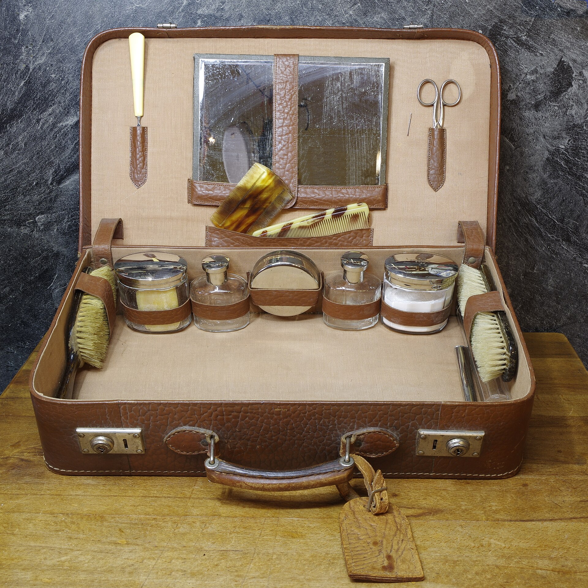 Un ancien nécessaire de voyage ouvert avec brosses, flacons et accessoires
