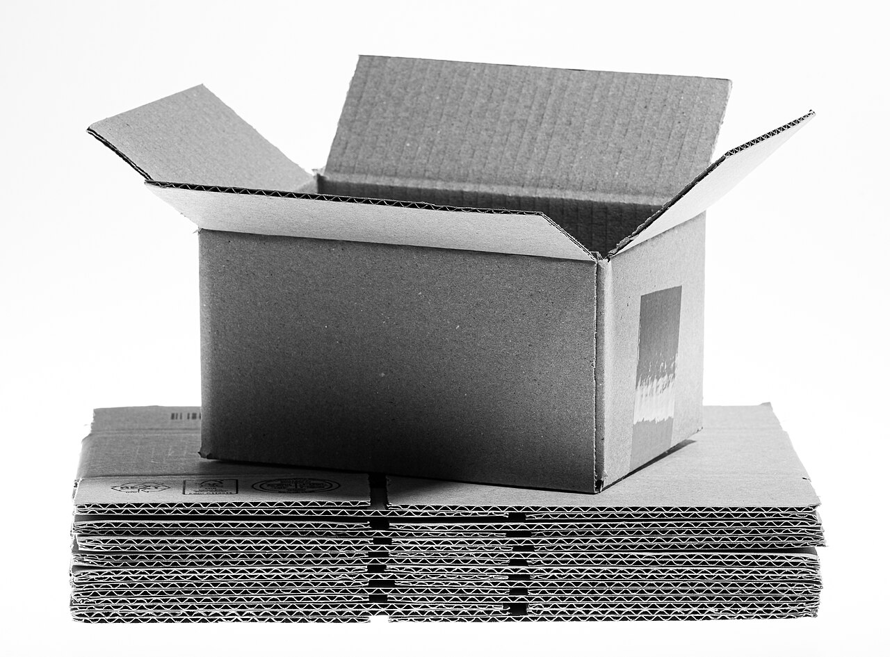 Un carton d’expédition ouvert repose sur une pile de cartons repliés.