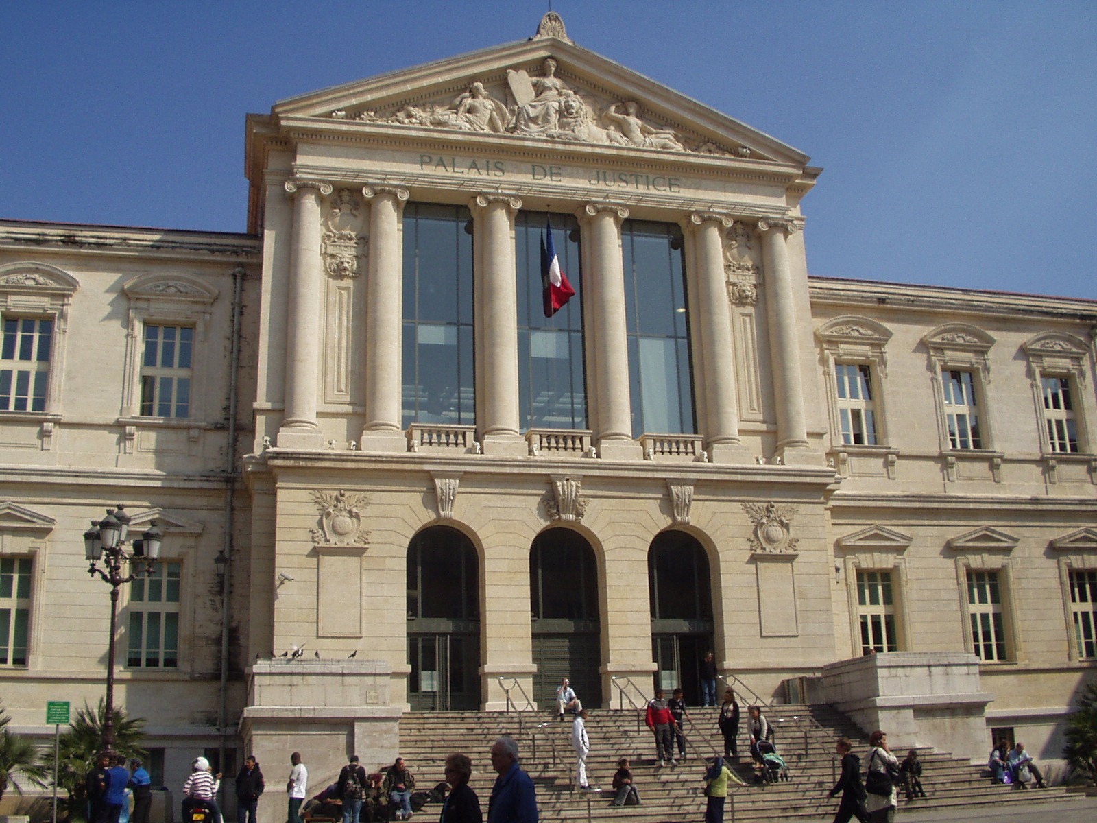 Façade à colonnes du palais de justice de Nice, surmontée de son fronton et du drapeau français