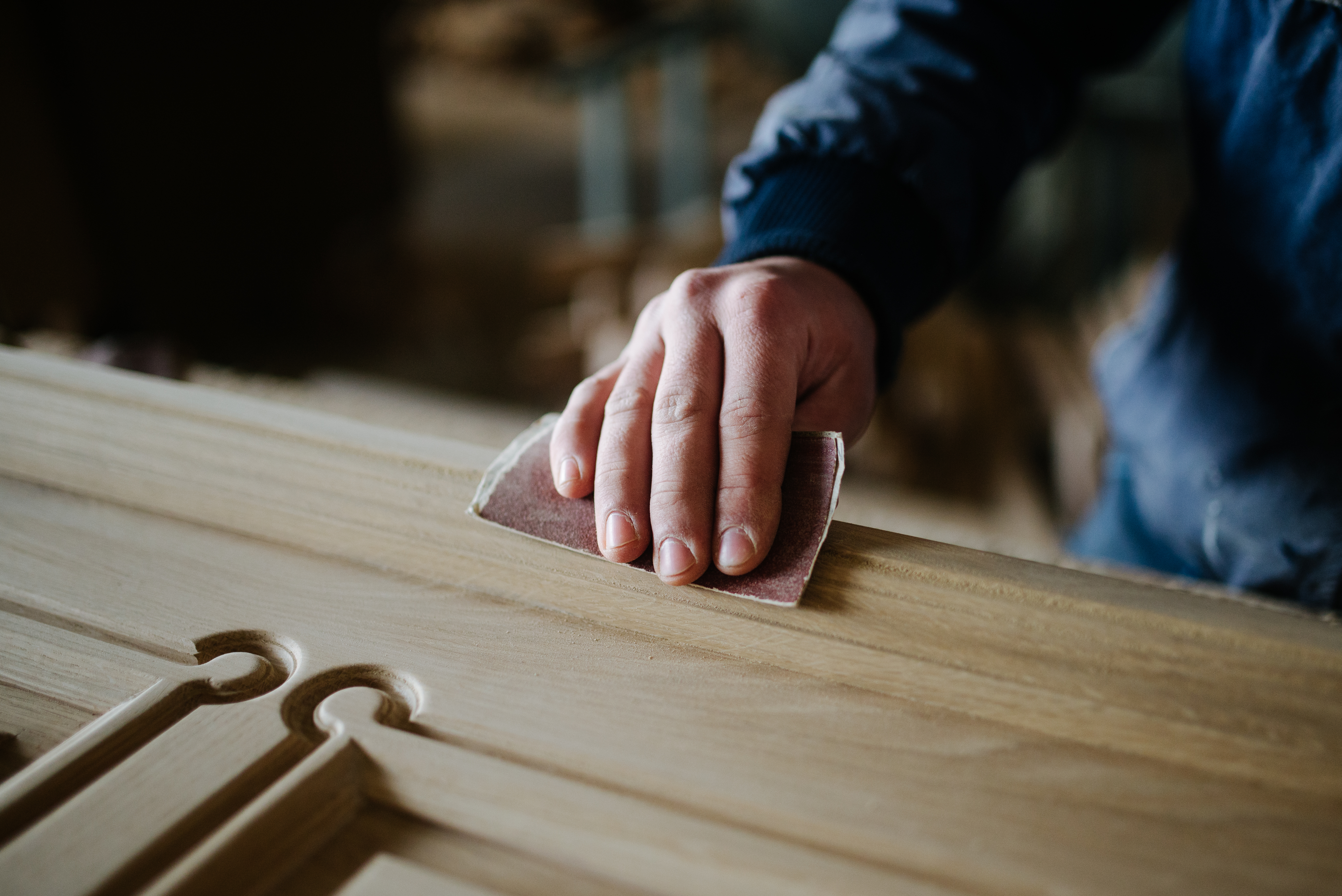Une main ponçant une pièce de bois au papier abrasif