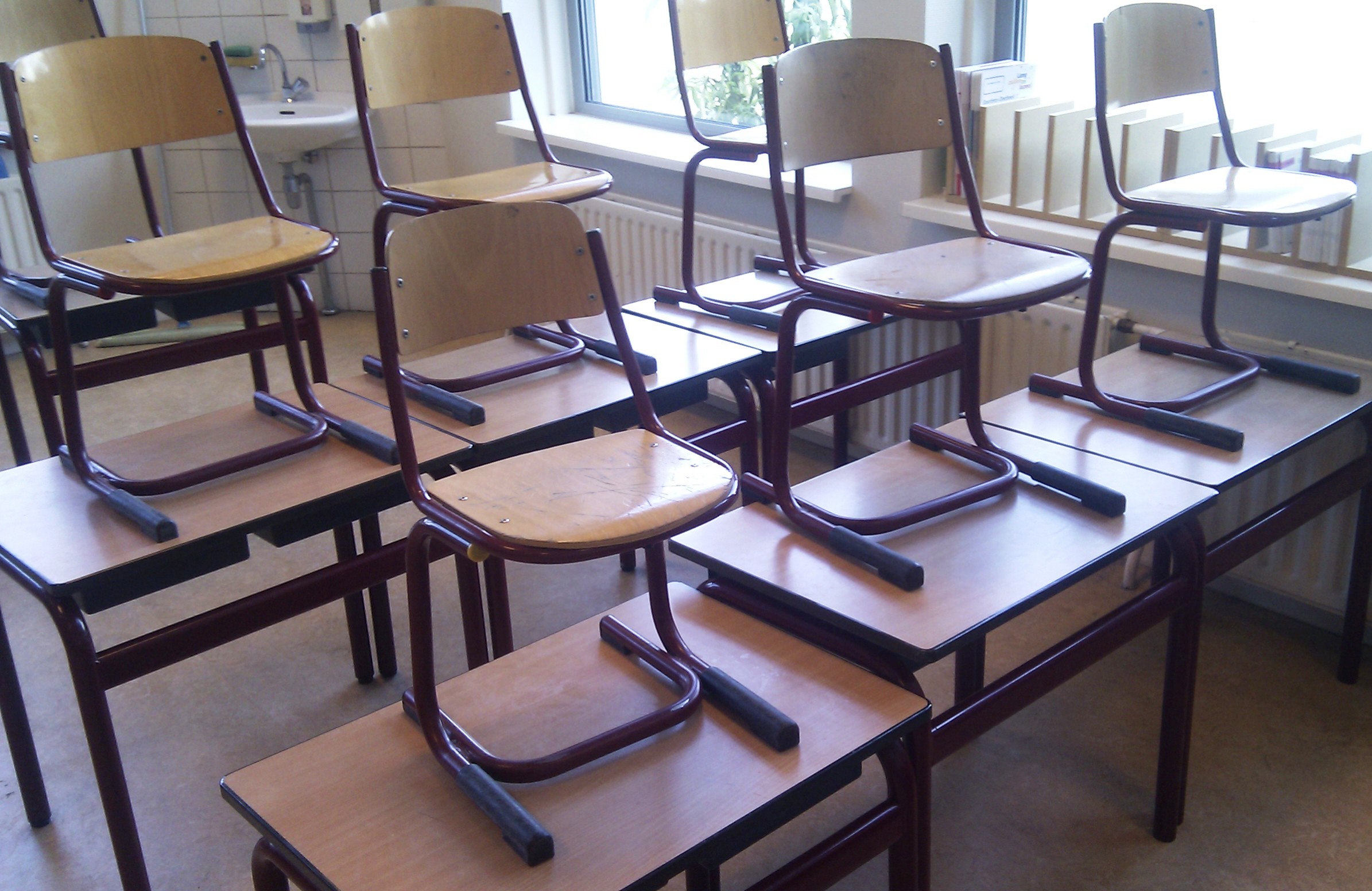 Des chaises posées sur les tables dans une salle de classe vide