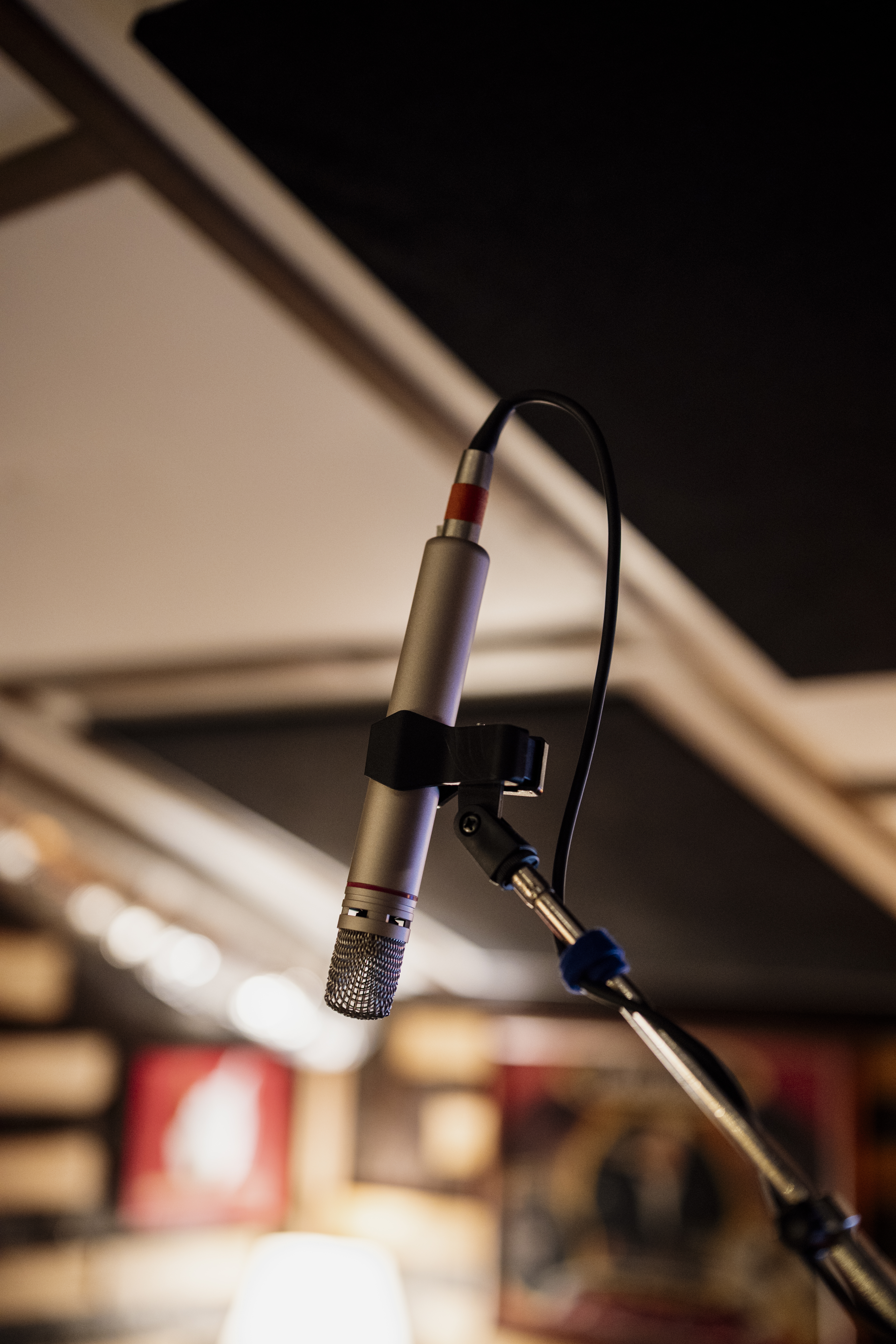 Un microphone argenté fixé à un pied dans un studio d’enregistrement.